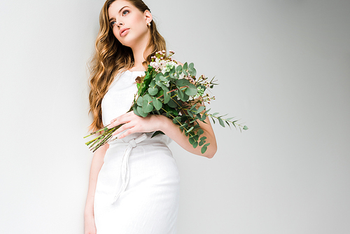 low angle view of girl in dress holding bouquet of chamelaucium and chrysanthemum flowers with eucalyptus leaves on white