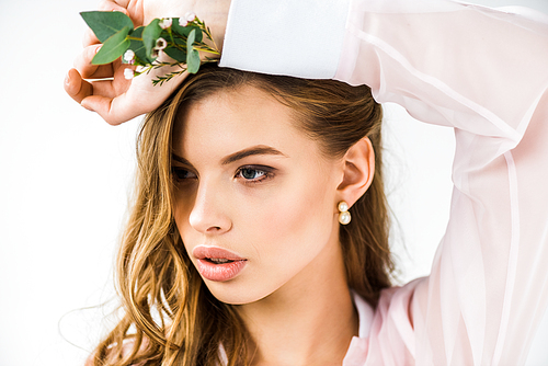 beautiful woman with flowers and green eucalyptus leaves in hand on white