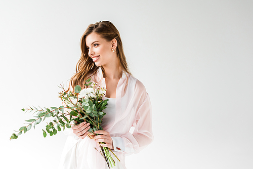 cheerful girl holding flowers and green eucalyptus leaves on white