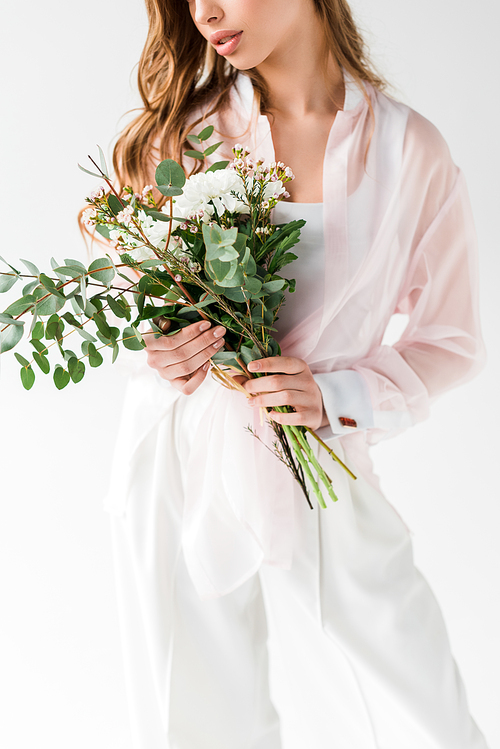 cropped view of girl holding flowers with green eucalyptus leaves on white