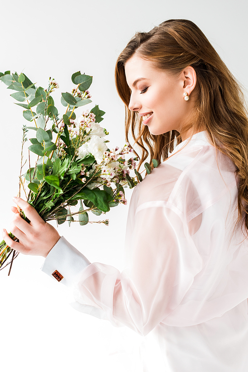happy woman smelling flowers with green eucalyptus leaves on white
