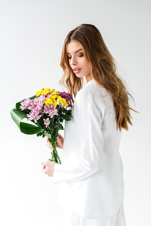 attractive girl looking at bouquet of wildflowers on white