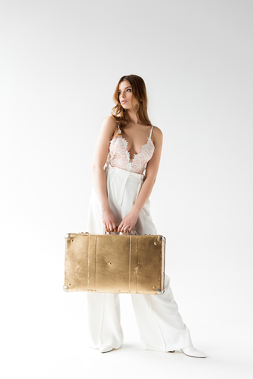 stylish pretty girl holding suitcase while standing on white