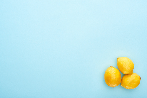 top view of ripe yellow lemons on blue background with copy space