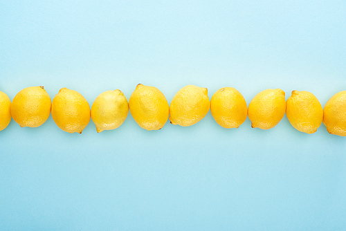 flat lay with ripe yellow lemons in line on blue background