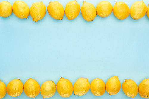 flat lay with ripe yellow lemons in lines on blue background