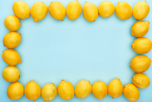 square frame of ripe yellow lemons on blue background with copy space