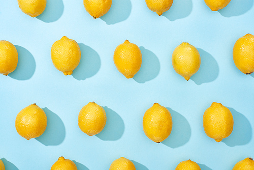pattern of ripe yellow lemons on blue background with shadows