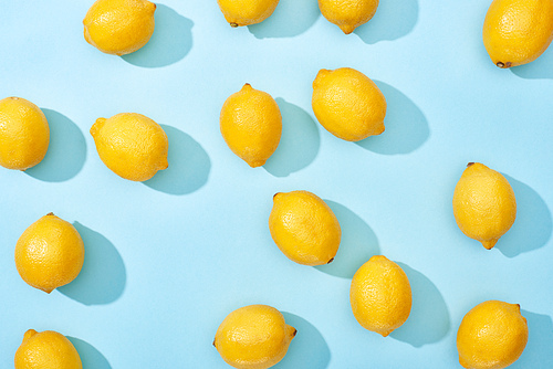 top view of ripe yellow lemons on blue background with shadows