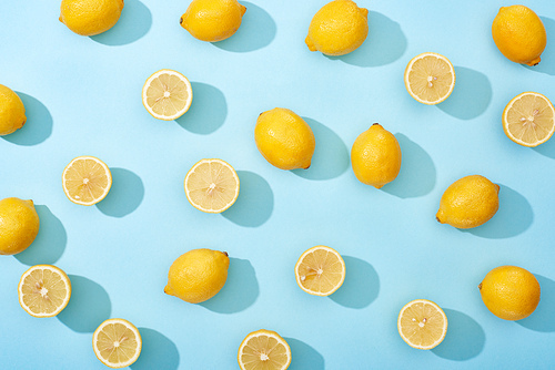 top view of whole and cut yellow lemons on blue background