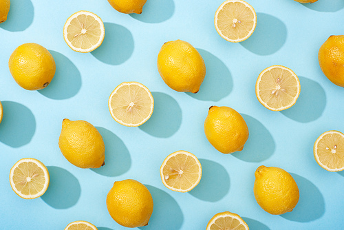top view of whole and cut yellow lemons on blue background