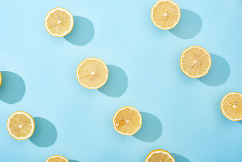 top view of ripe cut yellow lemons on blue background
