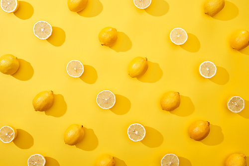 top view of ripe cut and whole lemons on yellow background