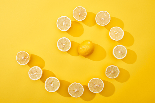 top view of ripe cut lemons in swirl on yellow background
