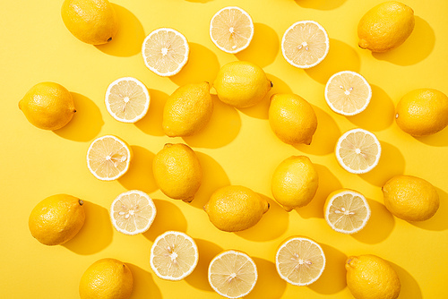 top view of ripe cut and whole lemons arranged in round frame on yellow background