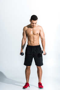 handsome mixed race man holding dumbbells and looking down on white