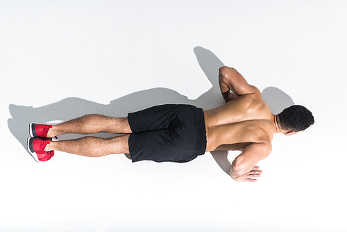 overhead view of shirtless sportive man doing push ups on white