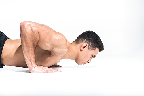 handsome mixed race man with muscular torso doing push ups on white