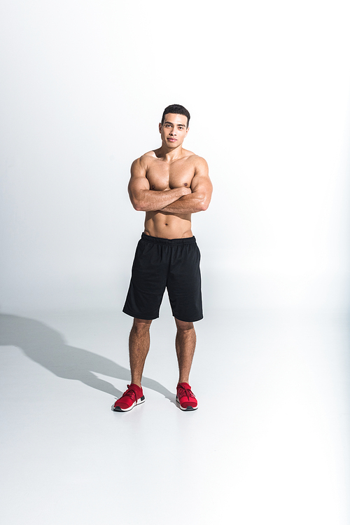 handsome sportive mixed race man in black shorts and red sneakers  on white