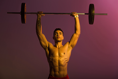 handsome athletic mixed race man lifting barbell on purple background