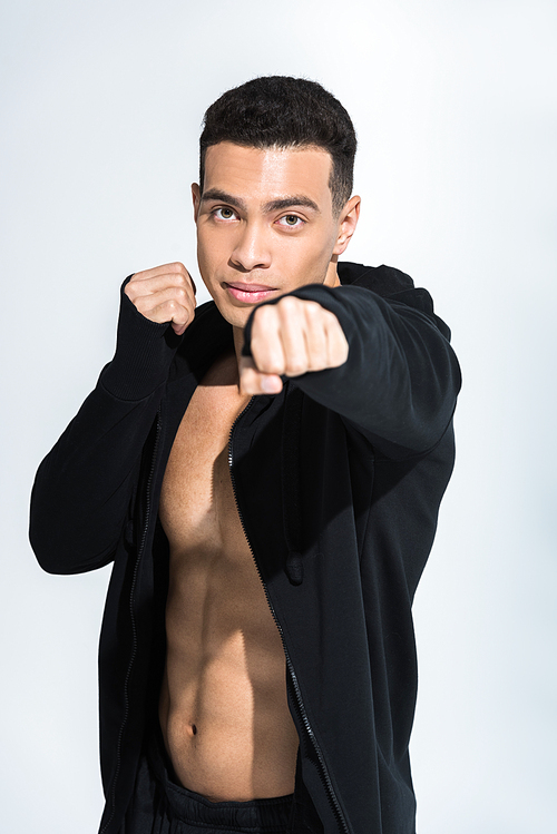 handsome mixed race man in black sports jacket warming up and  on white