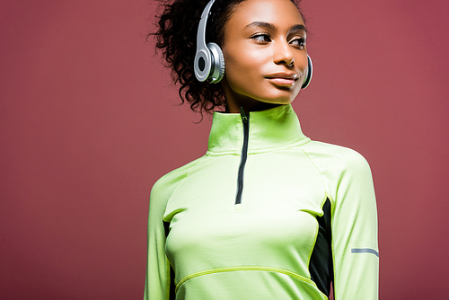beautiful african american sportswoman in headphones looking away isolated on brown with copy space