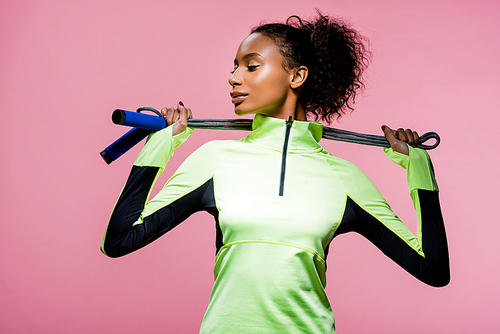 beautiful african american sportswoman posing with skipping rope isolated on pink