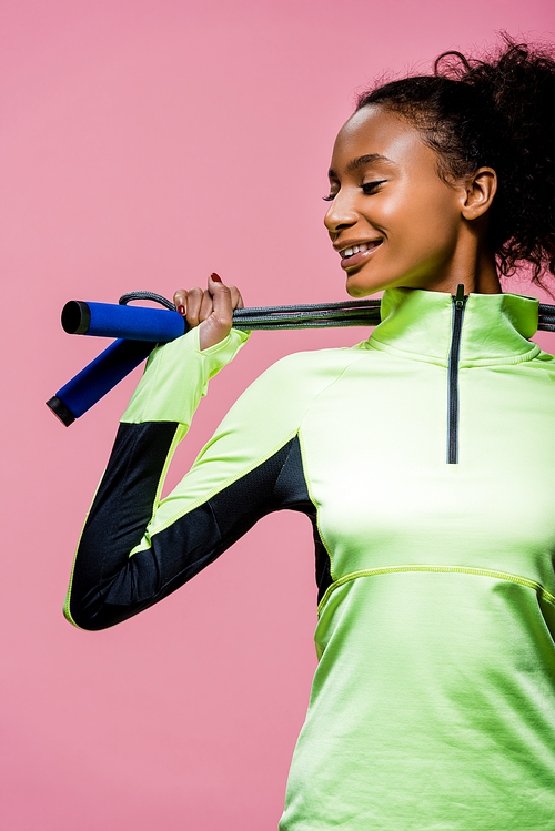 beautiful african american sportswoman posing with skipping rope isolated on pink