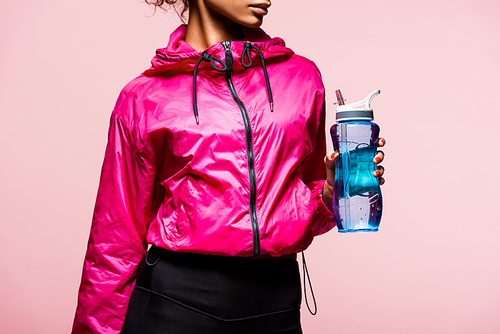 cropped view of african american sportswoman with sport bottle isolated on pink