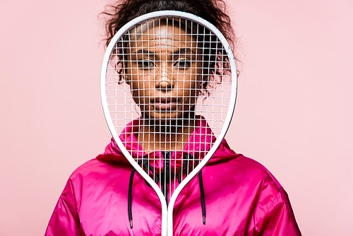 beautiful african american sportswoman  while covering face with tennis racket isolated on pink