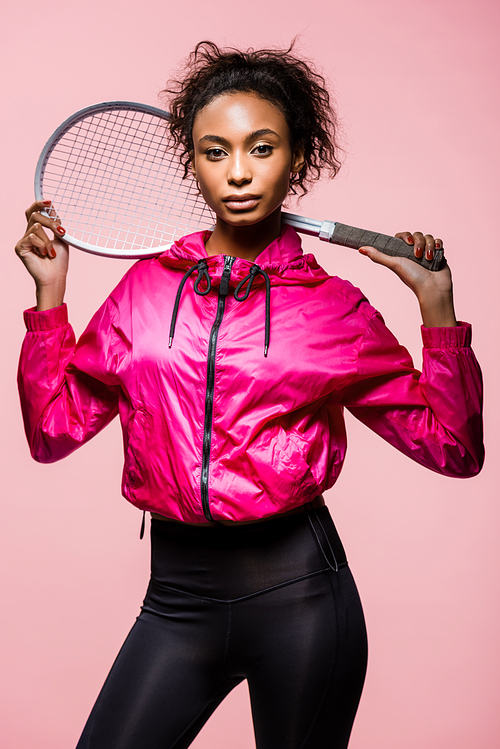 beautiful african american sportswoman with tennis racket posing and  isolated on pink