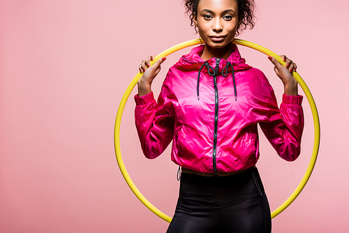 beautiful african american sportswoman  and holding hula hoop isolated on pink with copy space