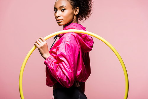 beautiful african american sportswoman holding hula hoop and  isolated on pink