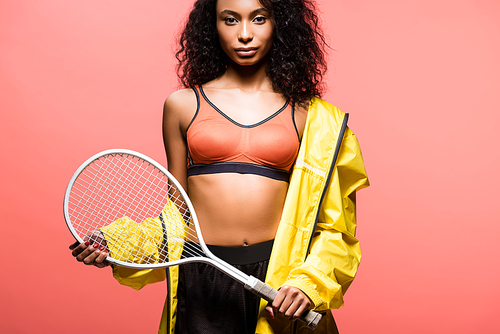 beautiful african american sportswoman  and holding tennis racket isolated on coral