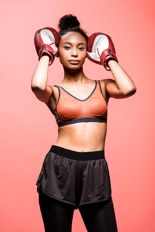 attractive african american sportswoman in boxing gloves  isolated on coral