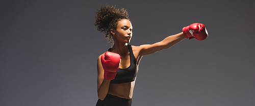 panoramic shot of beautiful athletic african american sportswoman boxing isolated on black with copy space