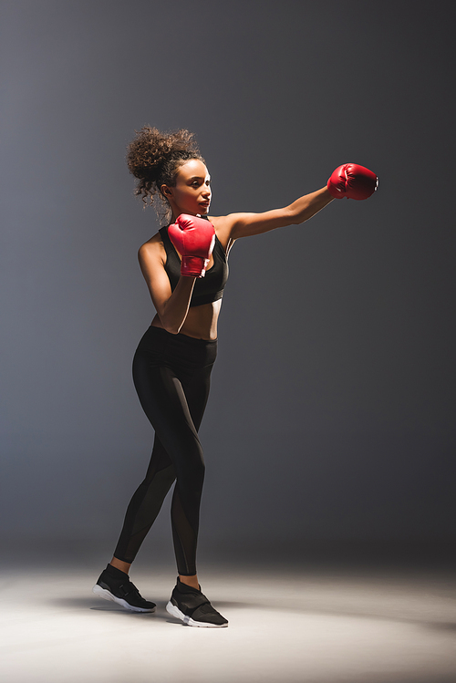 beautiful athletic african american sportswoman boxing on black