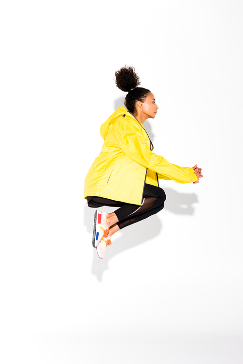 side view of athletic african american sportswoman jumping on white