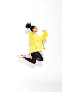 side view of beautiful athletic african american sportswoman jumping on white