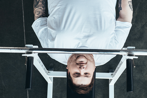 top view of Overweight tattooed man  while training with barbell at gym