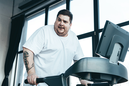 overweight tattooed man  and running on treadmill at sports center
