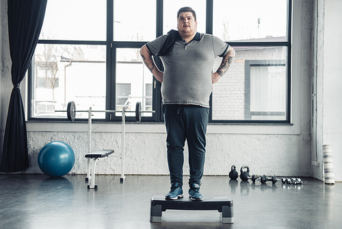 overweight man with towel standing on step platform at sports center