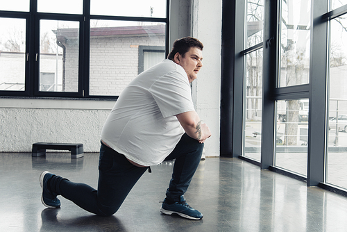 overweight man stretching legs at sports center with copy space