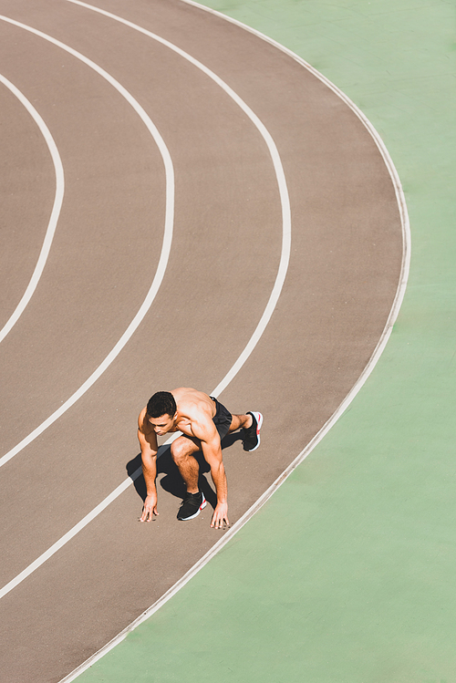 overhead view mixed race sportsman preparing to run at stadium