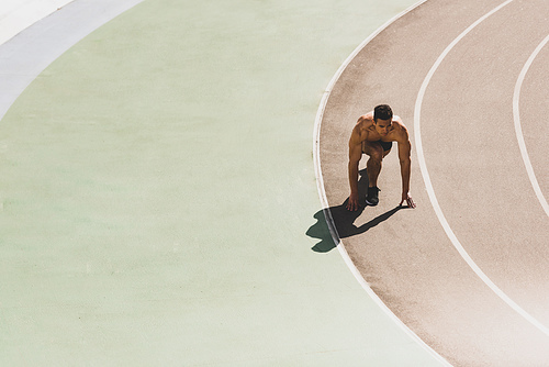 mixed race sportsman preparing to run at stadium