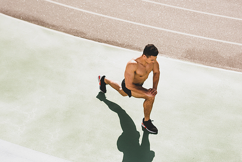 overhead view of shirtless mixed race sportsman stretching at stadium