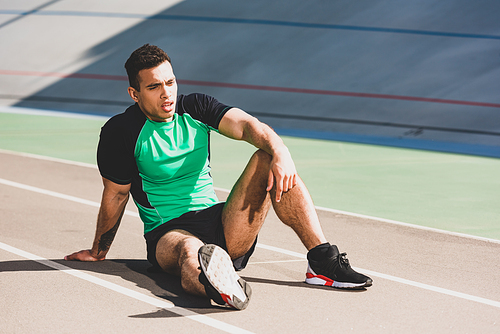 tired handsome mixed race sportsman sitting at stadium