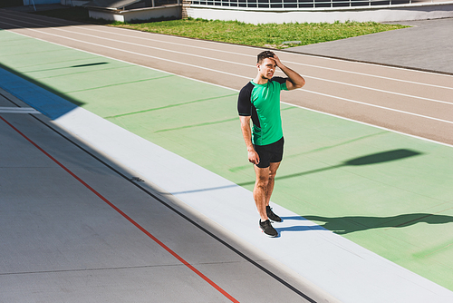 full length view of mixed race sportsman standing at stadium