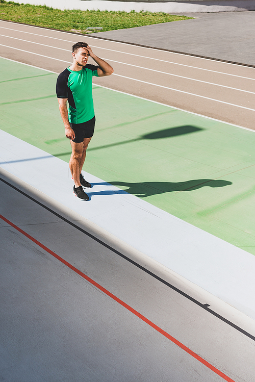 full length view of tired mixed race sportsman standing at stadium