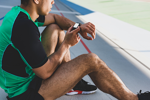 cropped view of sportsman using smartwatch at running track